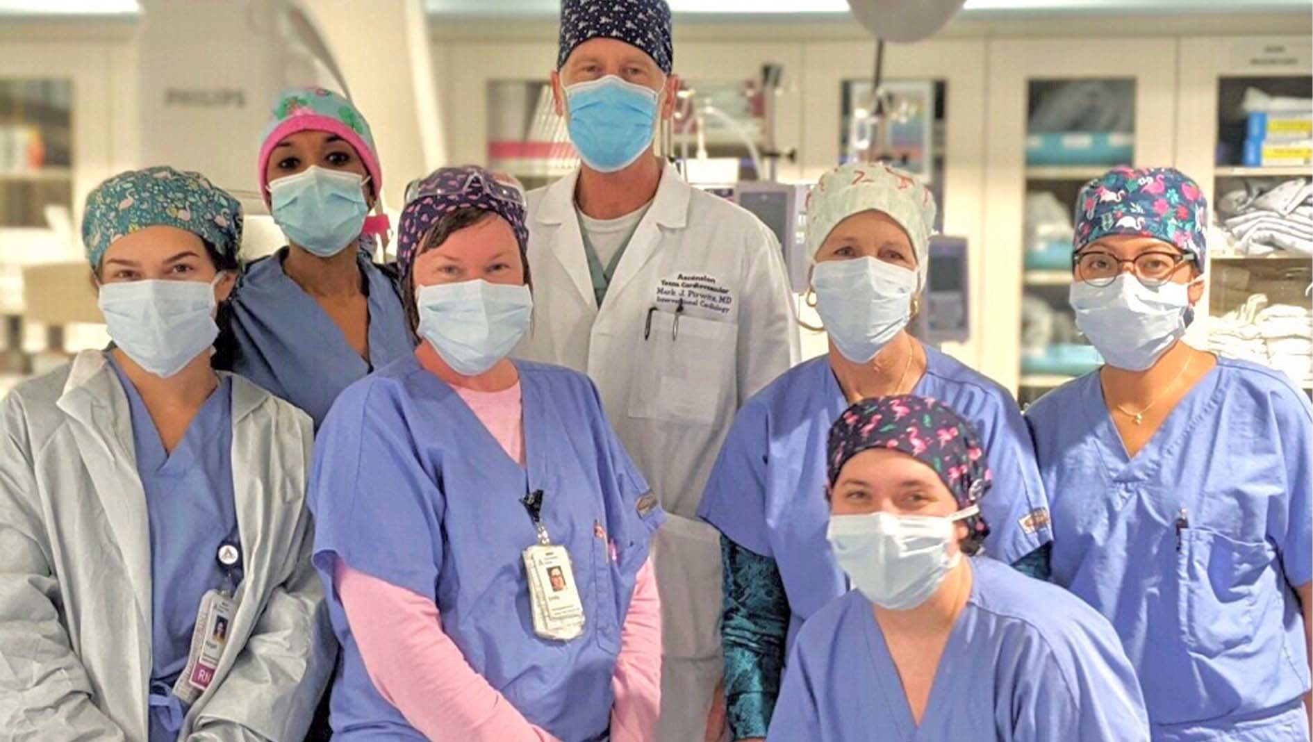Health care workers affiliated with the Cardiovascular Disease Fellowship, each wearing medical masks, post together for a group photo.