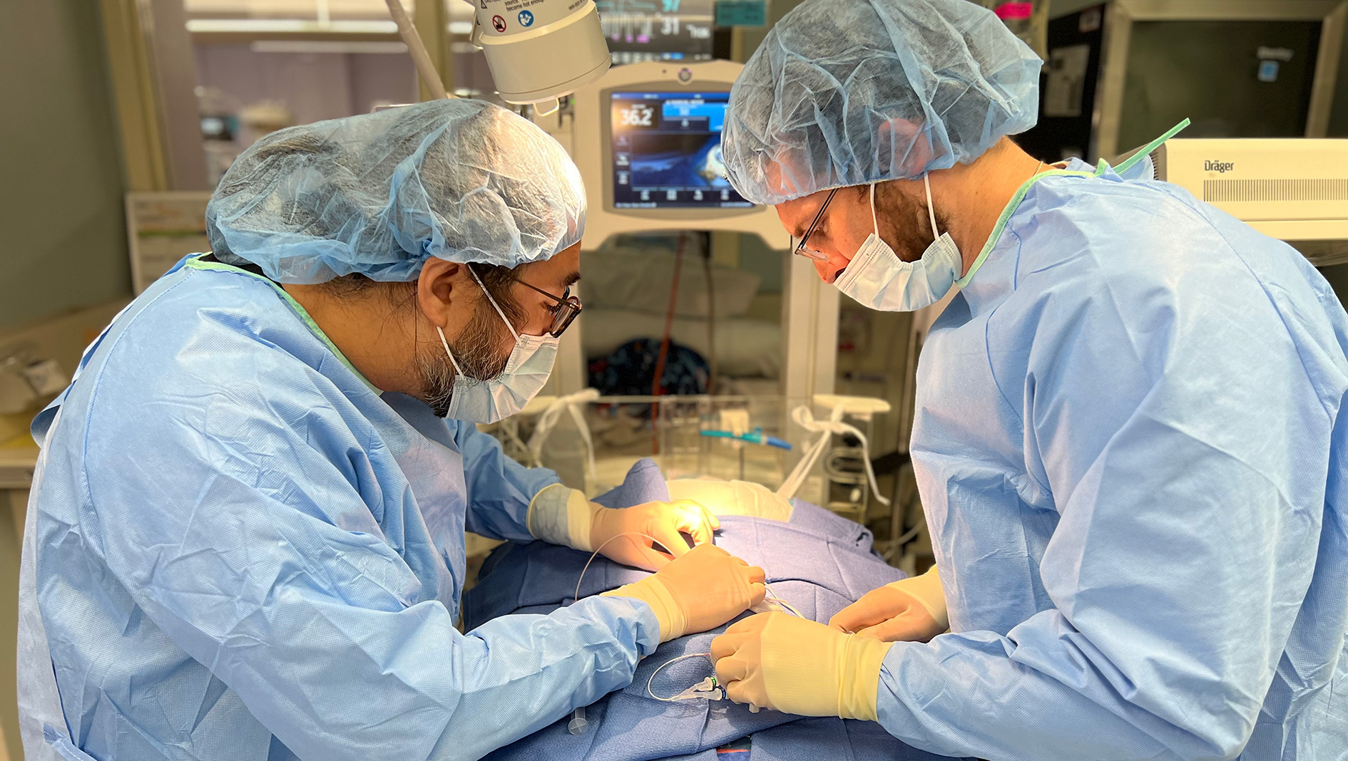 A fellow works with a faculty member to perform a procedure.