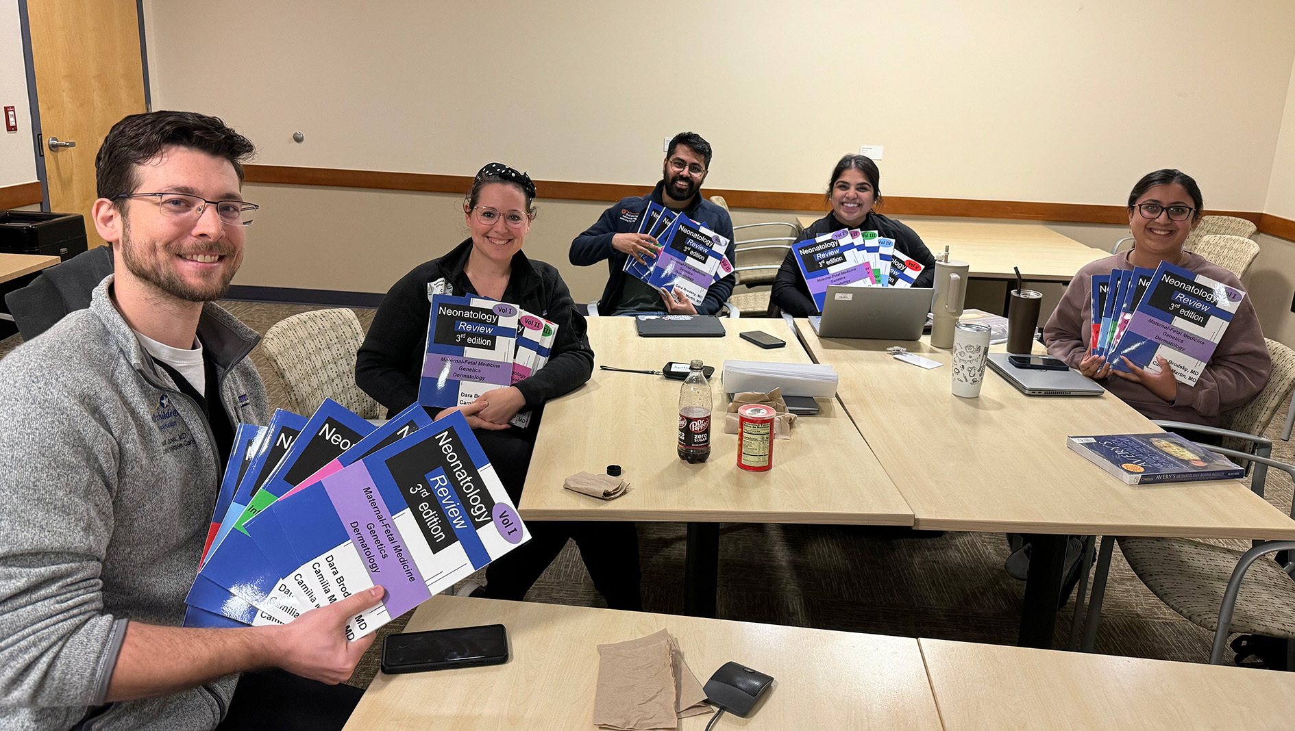 Group photo of NICU fellows with textbooks
