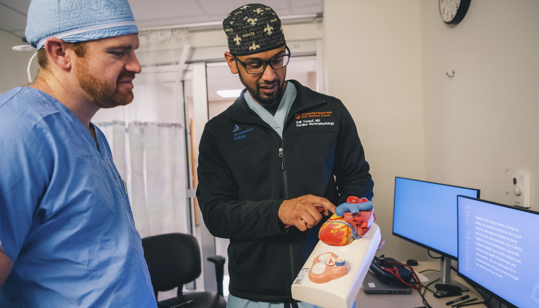 Fellows observe a heart model in an office.