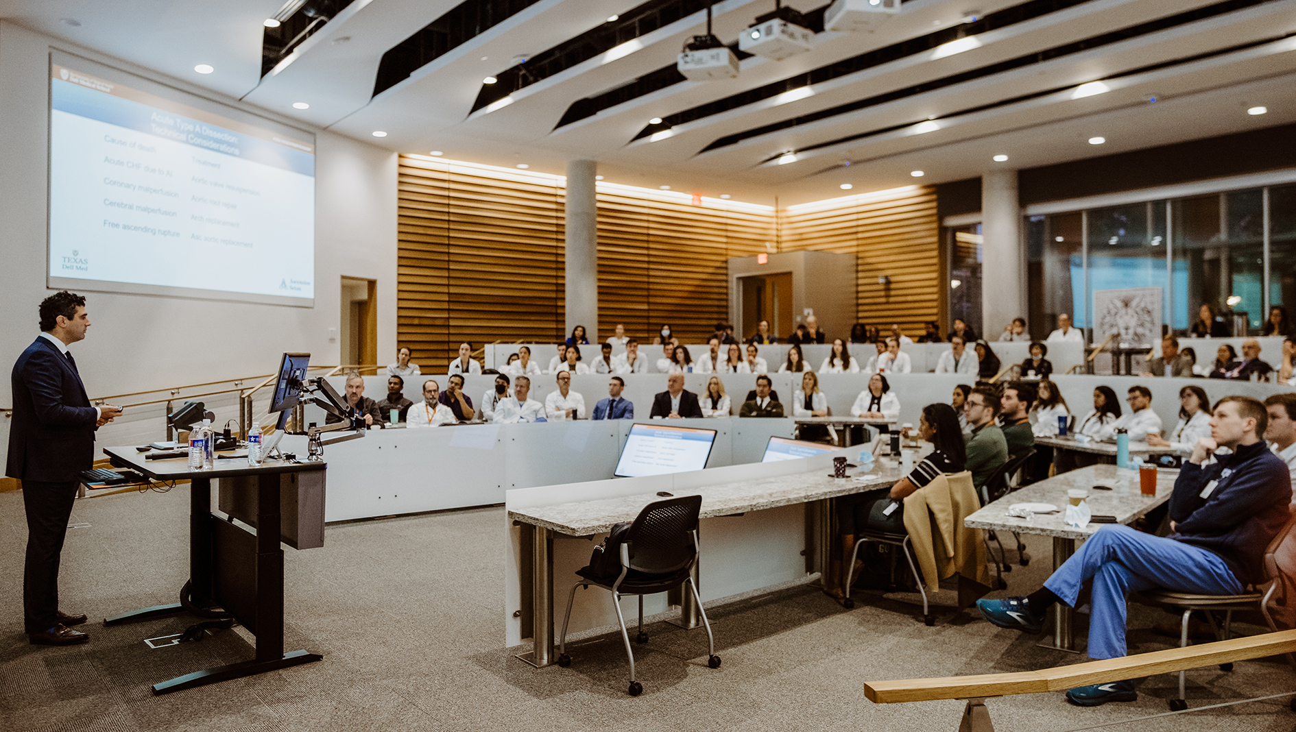 Surgery residents listen to a presentation in a large lecture hall