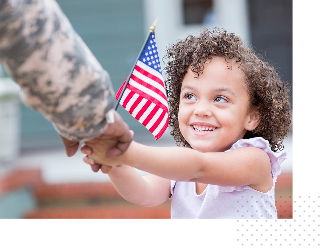 A young girl holds an American flag and greets her family member