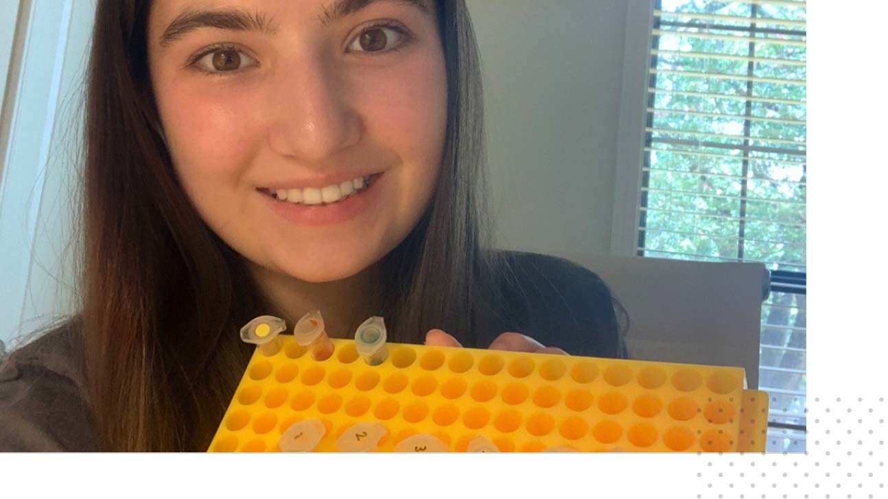 Nell, a 2022 SHE participant, holds a test tube tray with a number of tubes slotted in.