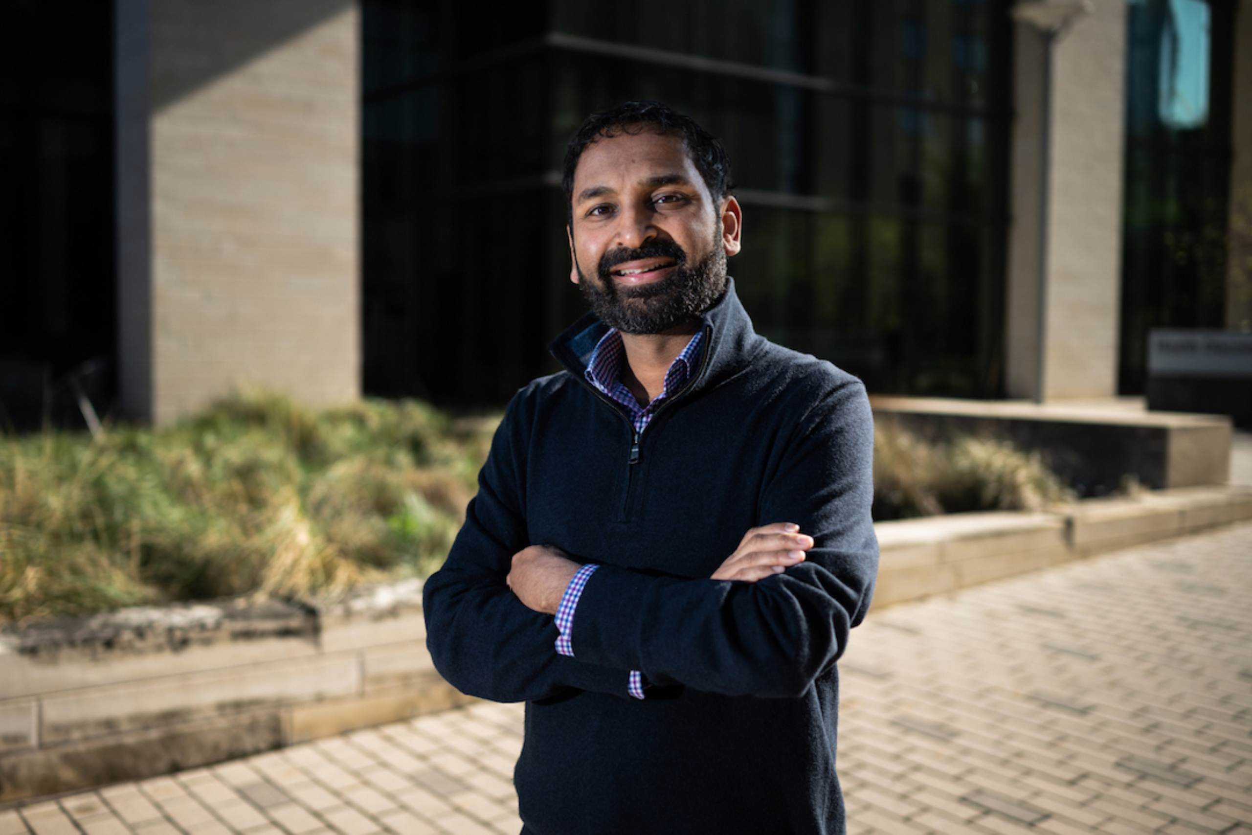 Ammar Ahmed stands outside with his arms crossed, smiling at the camera.
