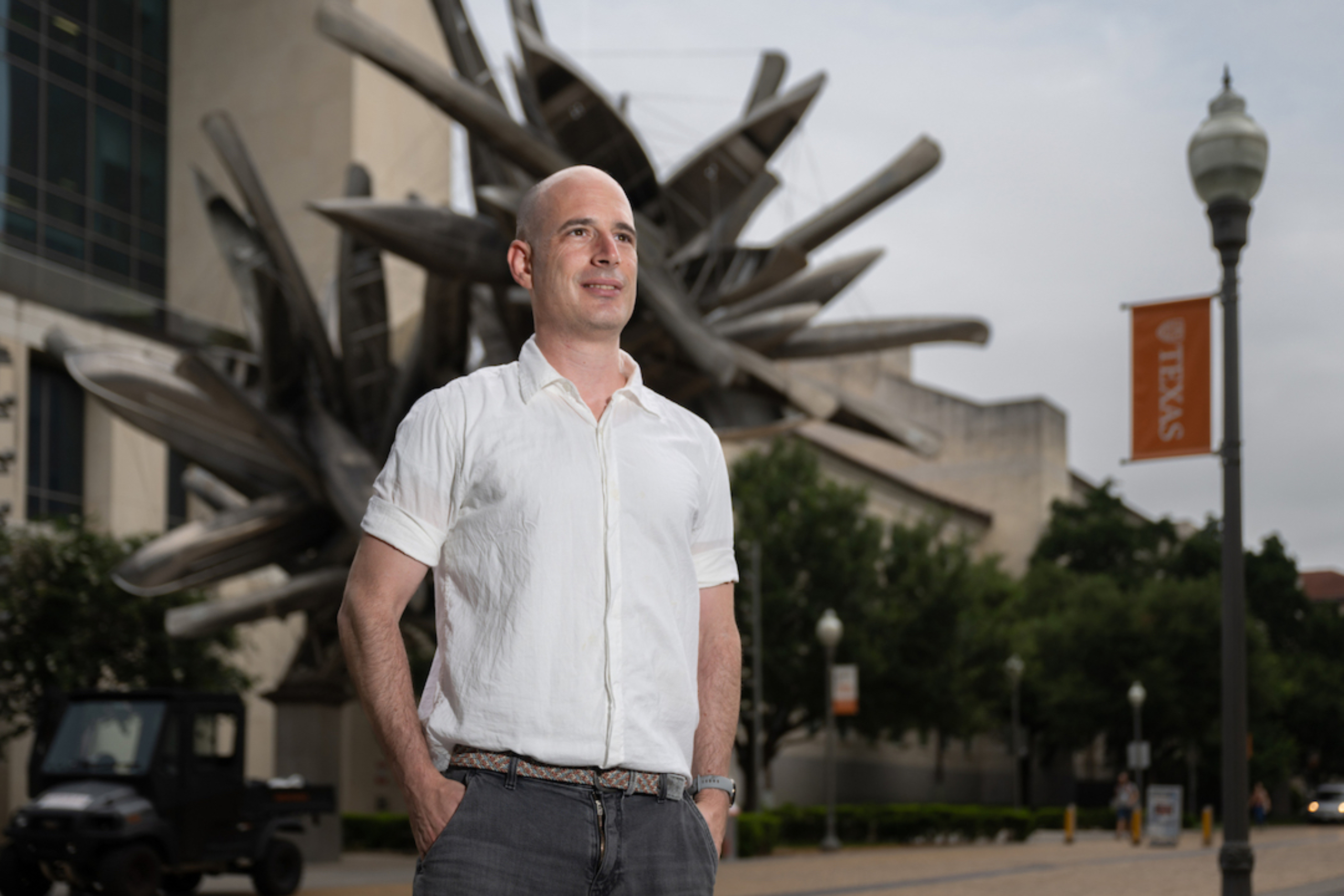 Arbel Harpak stands in front of a statue, looking away from the camera.