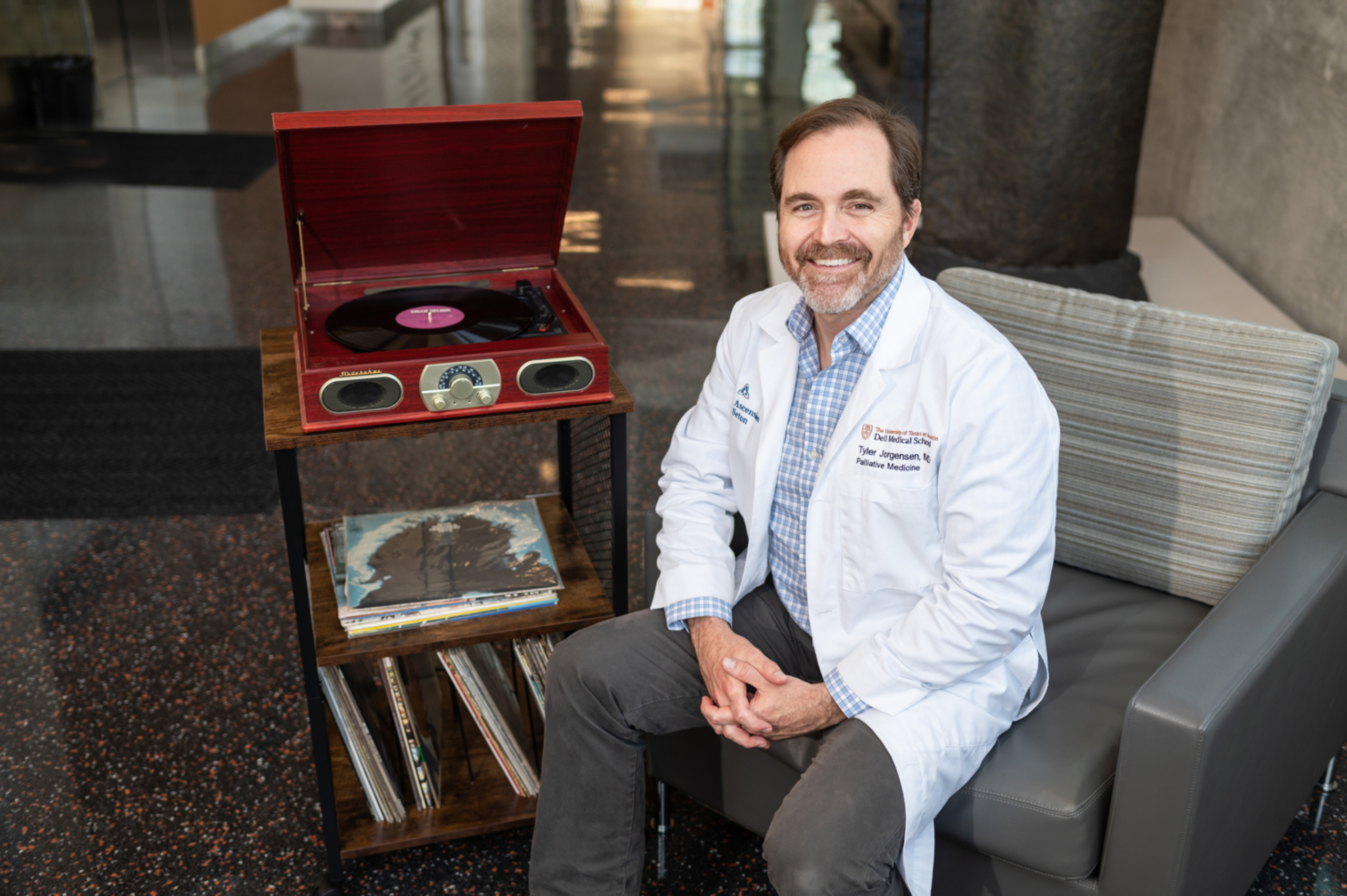 Portrait of Tyler Jorgensen seated next to record player and vinyl records.
