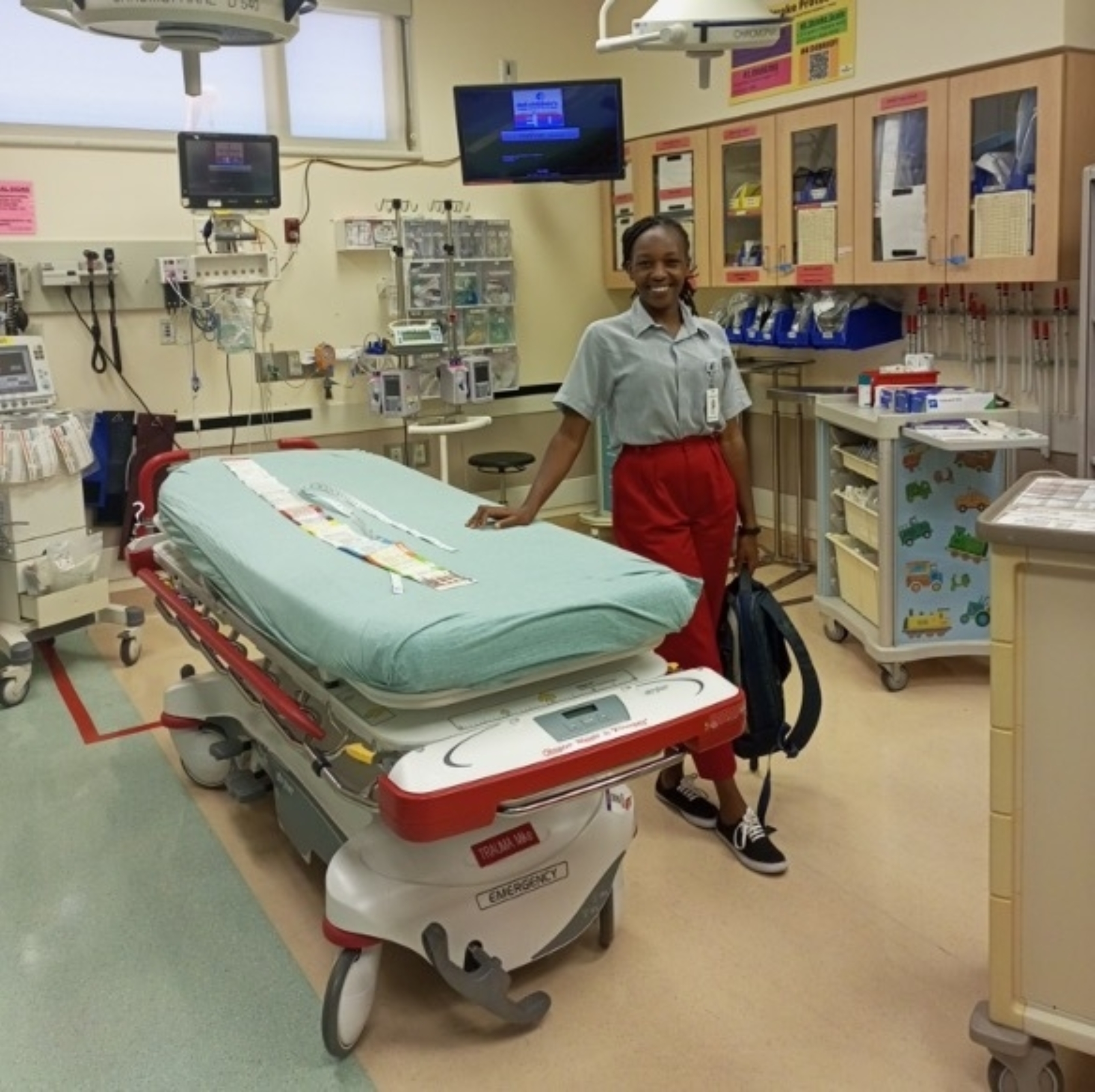 An international exchange student from Kenya stands by a medical bed inside a medical facility.