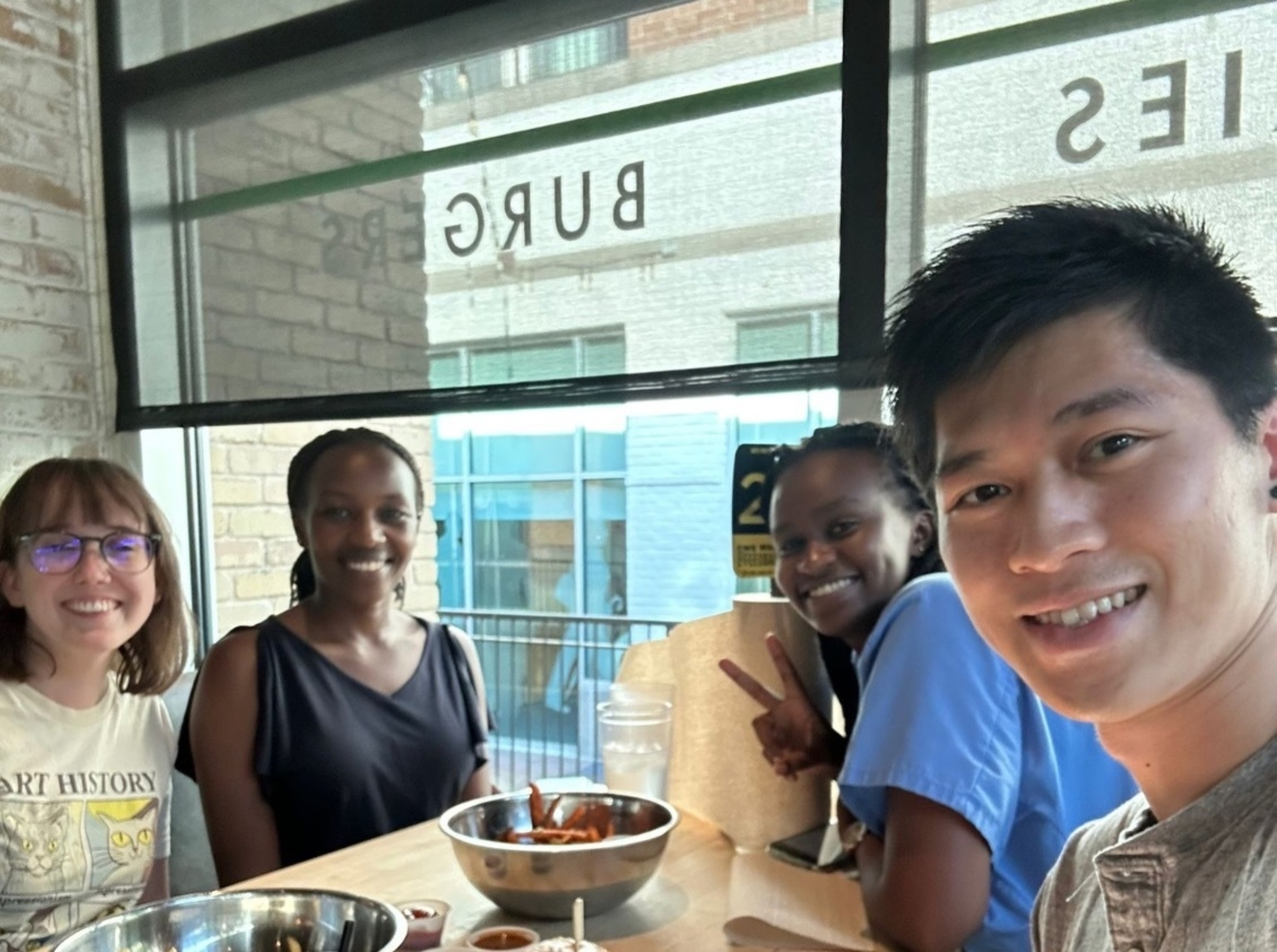 International exchange students from Kenya sit at a restaurant table with Dell Med students.