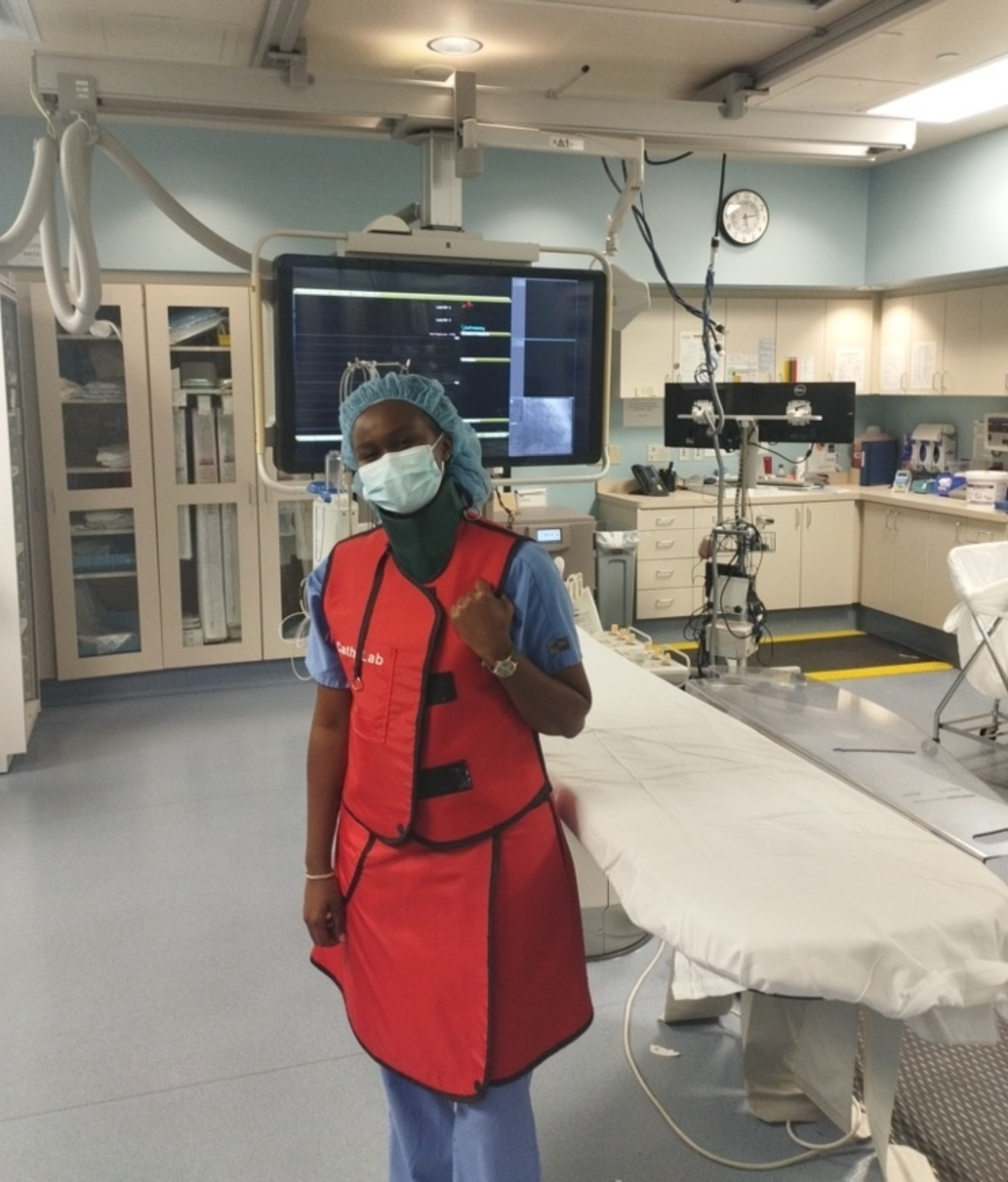An international exchange student from Kenya wears medical scrubs and stands by an operating room table.