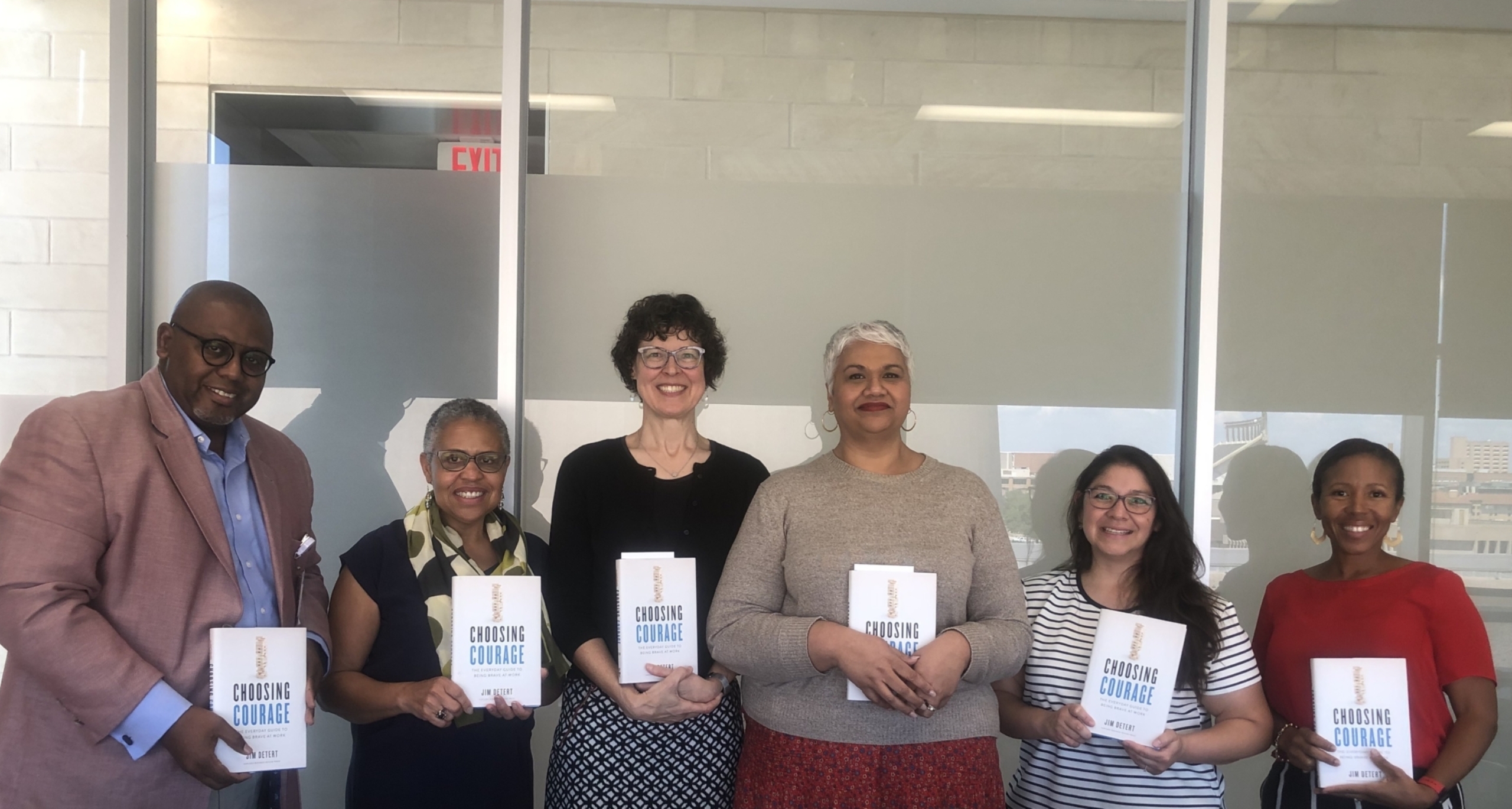 Six people stand in a row, each holding a book titled "Choosing Courage."
