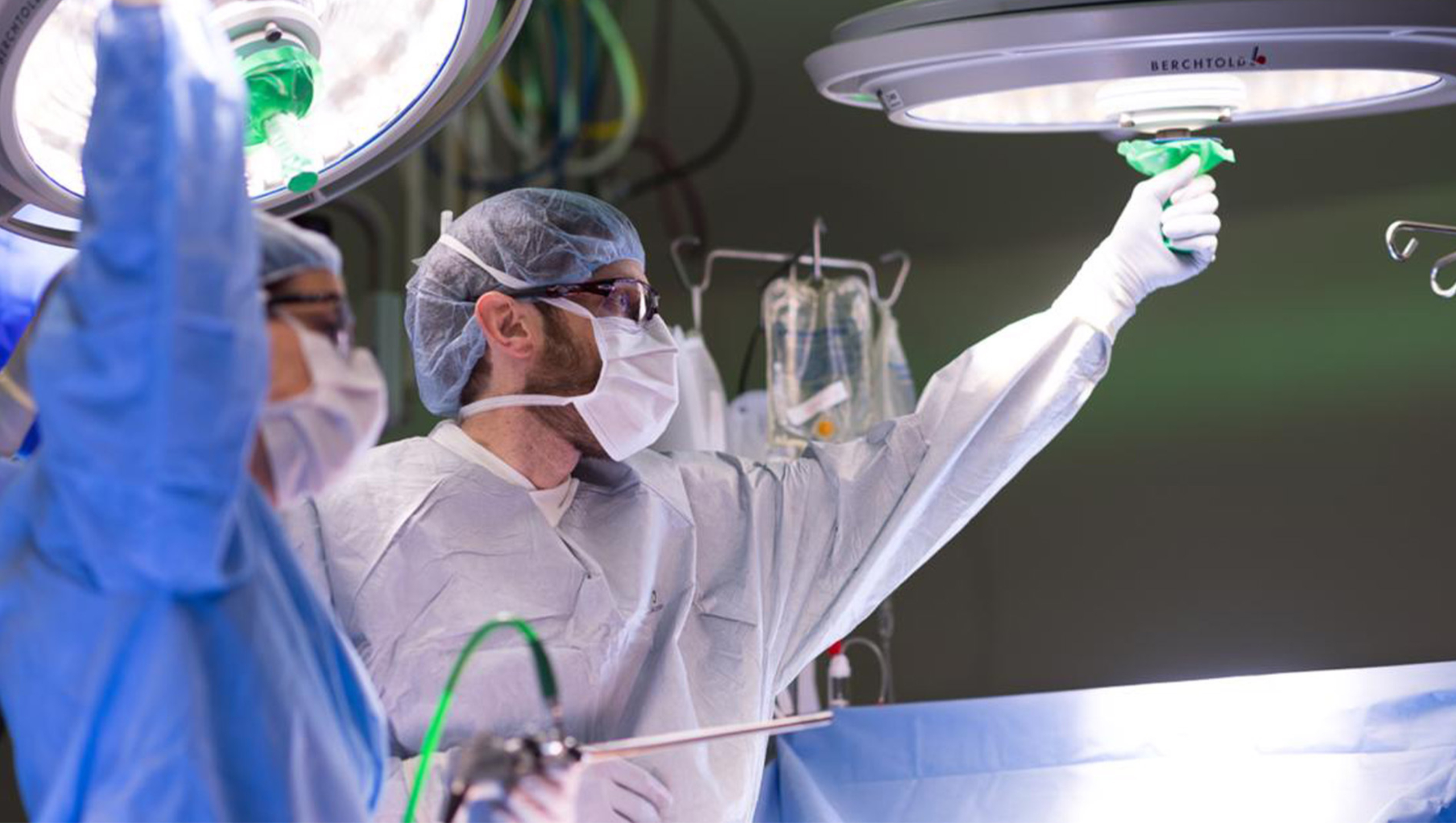 Two transplant surgeons using operating room equipment during a surgical procedure.