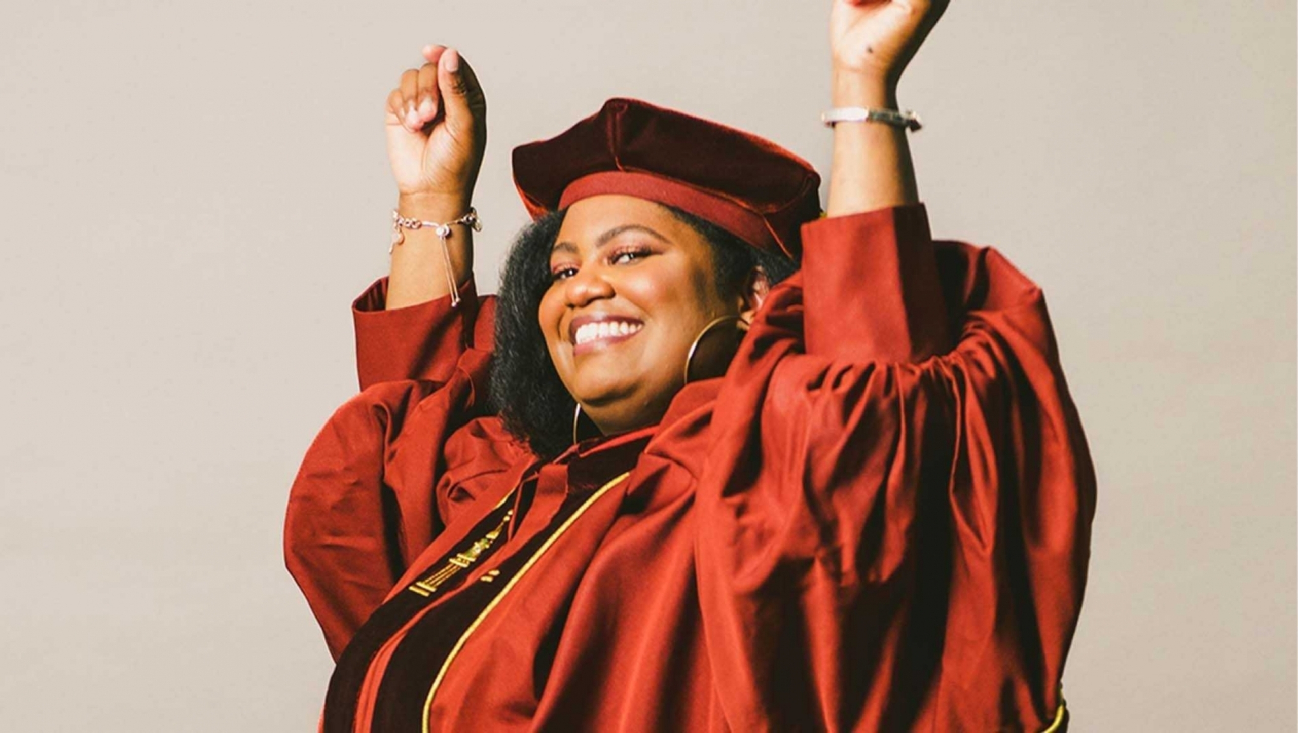 Ciaura Brown in a celebratory pose while wearing graduation regalia.