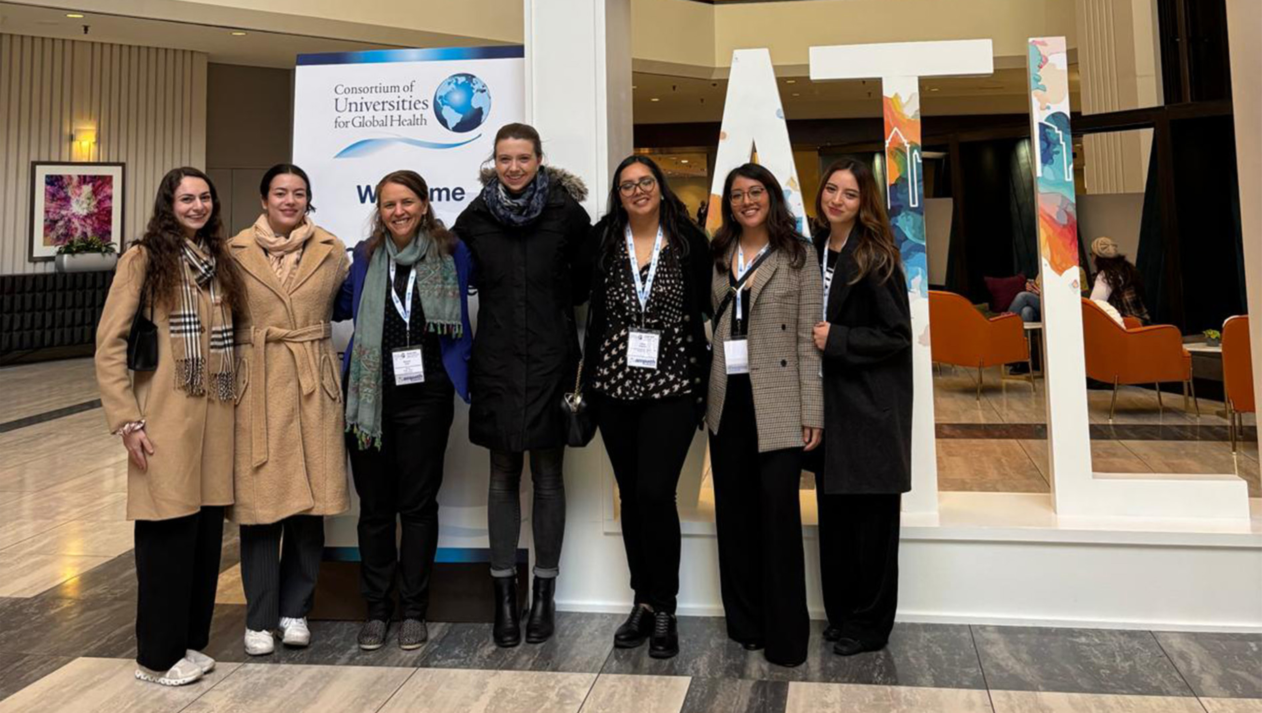 A group of people affiliated with the Division of Global Health stand together for a photo at a conference.