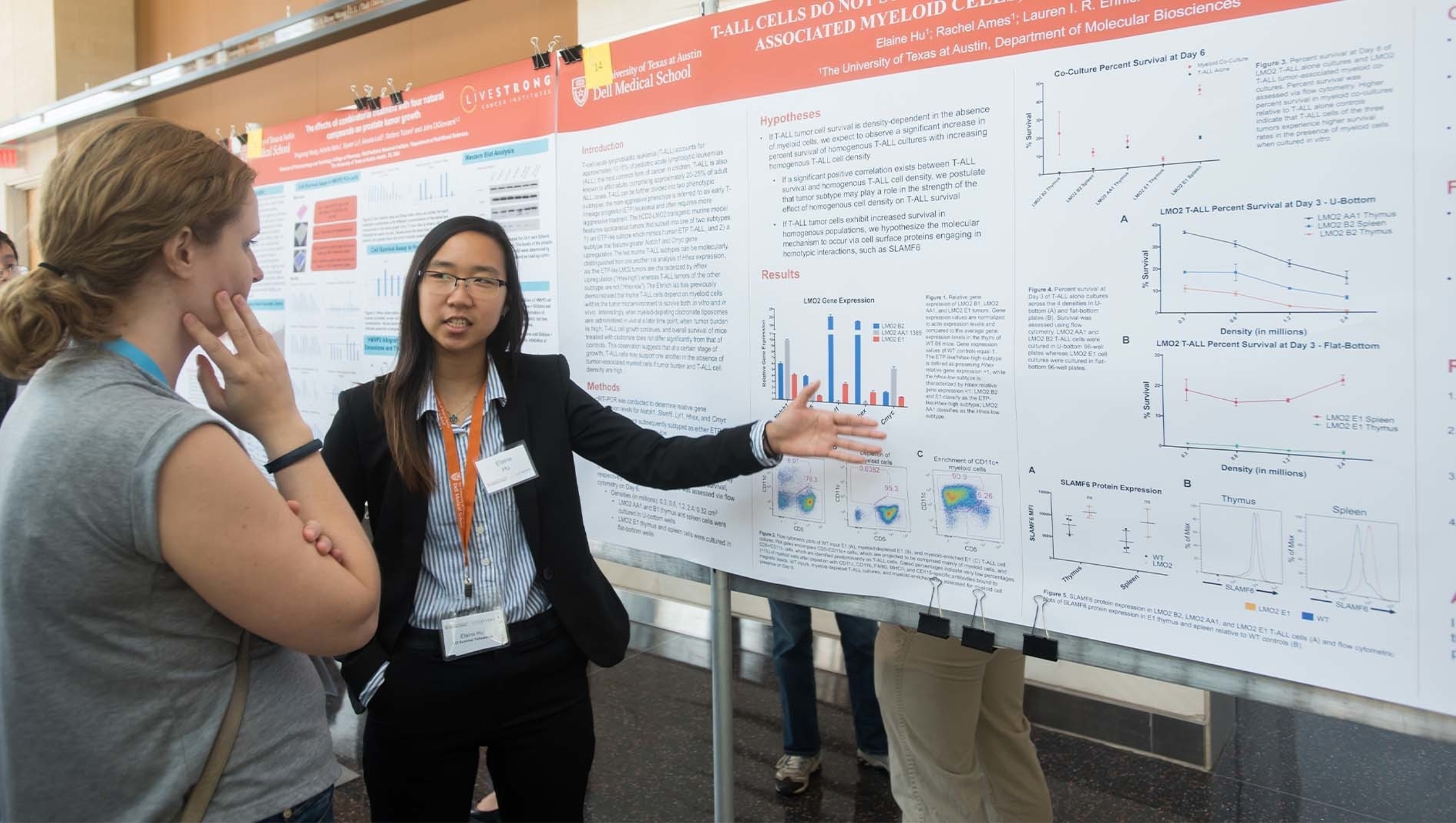 A woman presents a research poster to an individual.