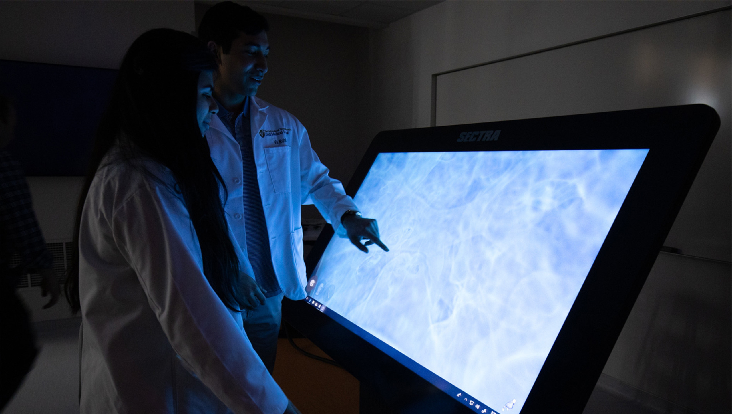 Two medical students manipulate a data visualization device.