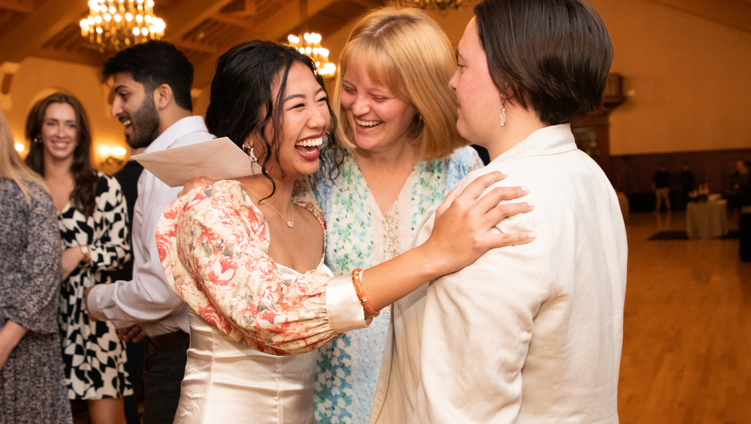A small group of women gather for a joyous embrace, celebrating Match Day results.