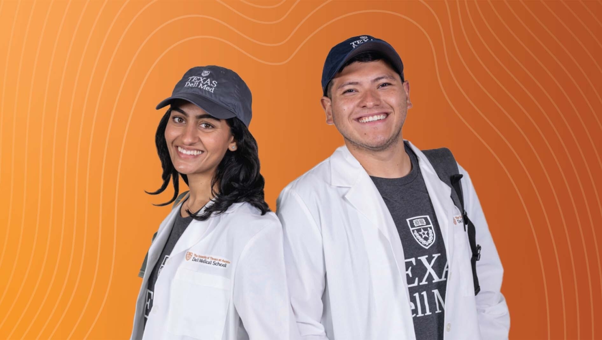Zahra Ansari and Giezi Contreras in white physicians coats and Dell Med baseball caps.