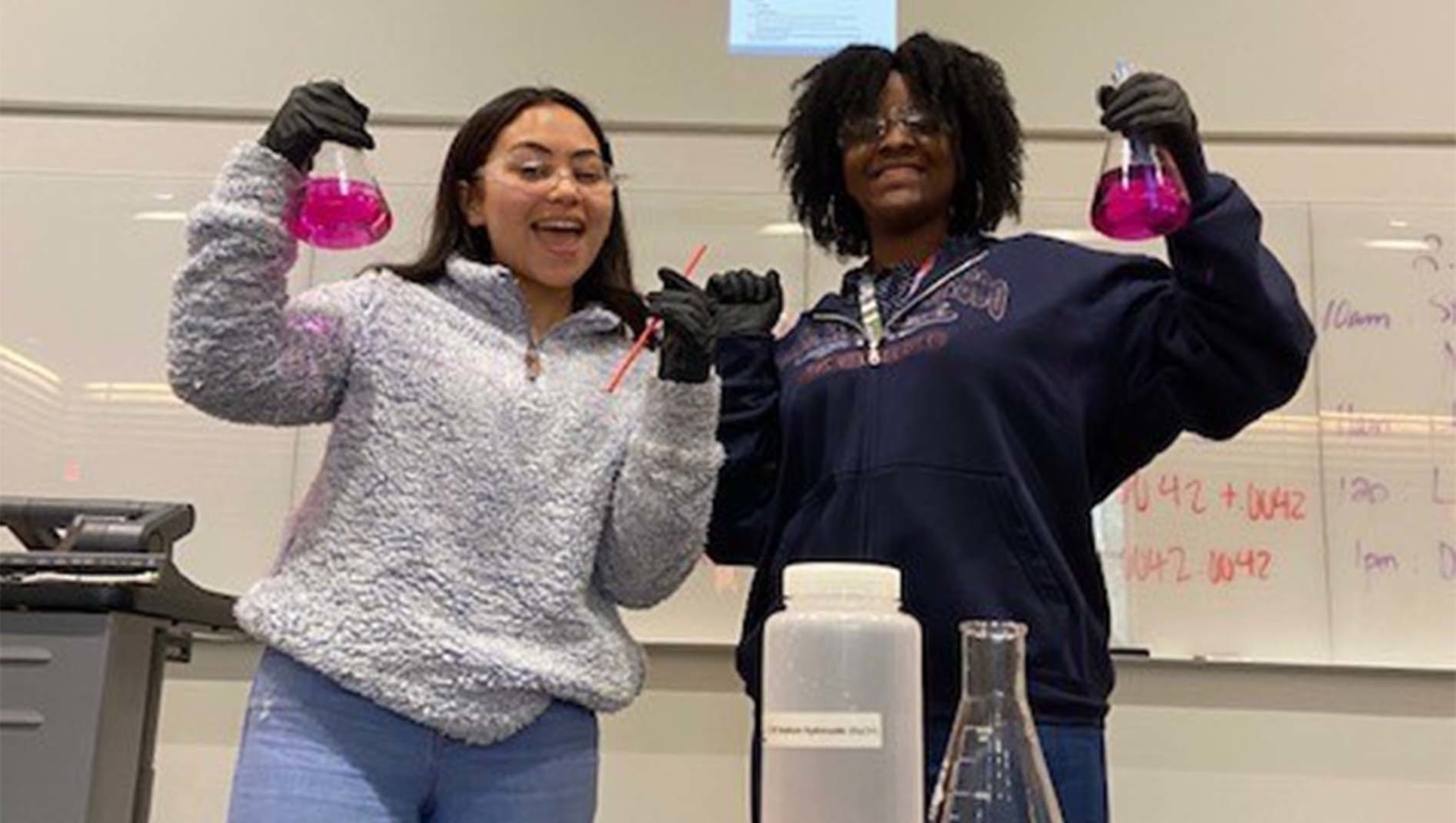 Two members of the Summer Chemistry for Pre-Health Professions program holding science flasks. 