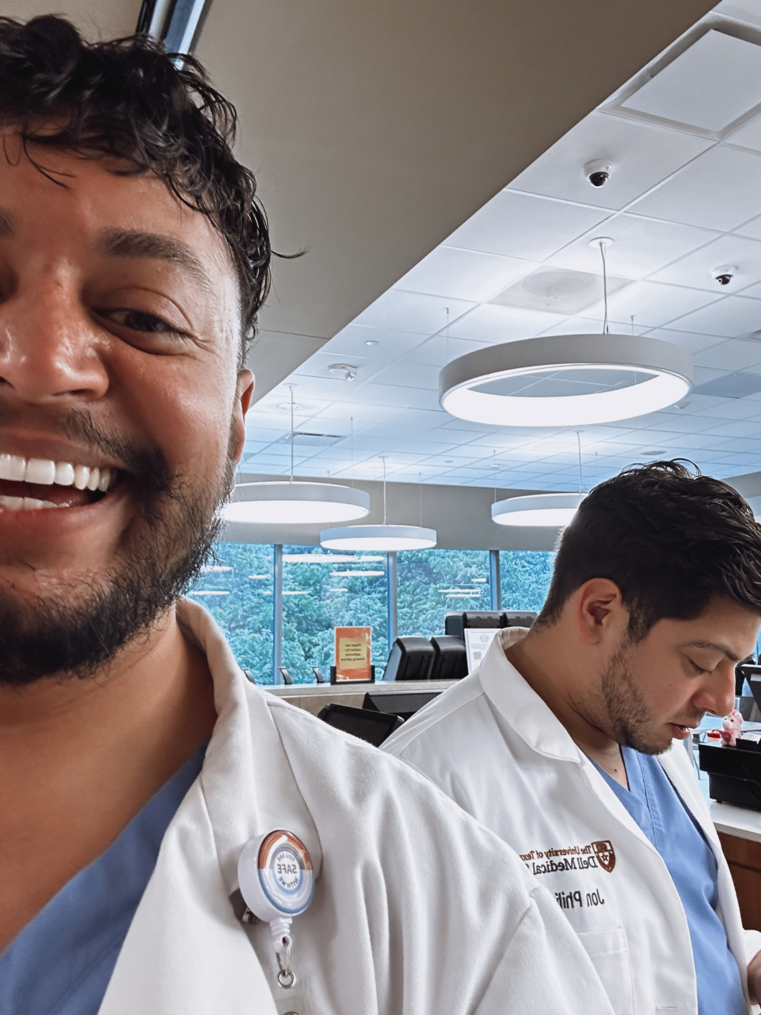 A Dell Medical School student takes a jovial selfie inside a lecture hall.