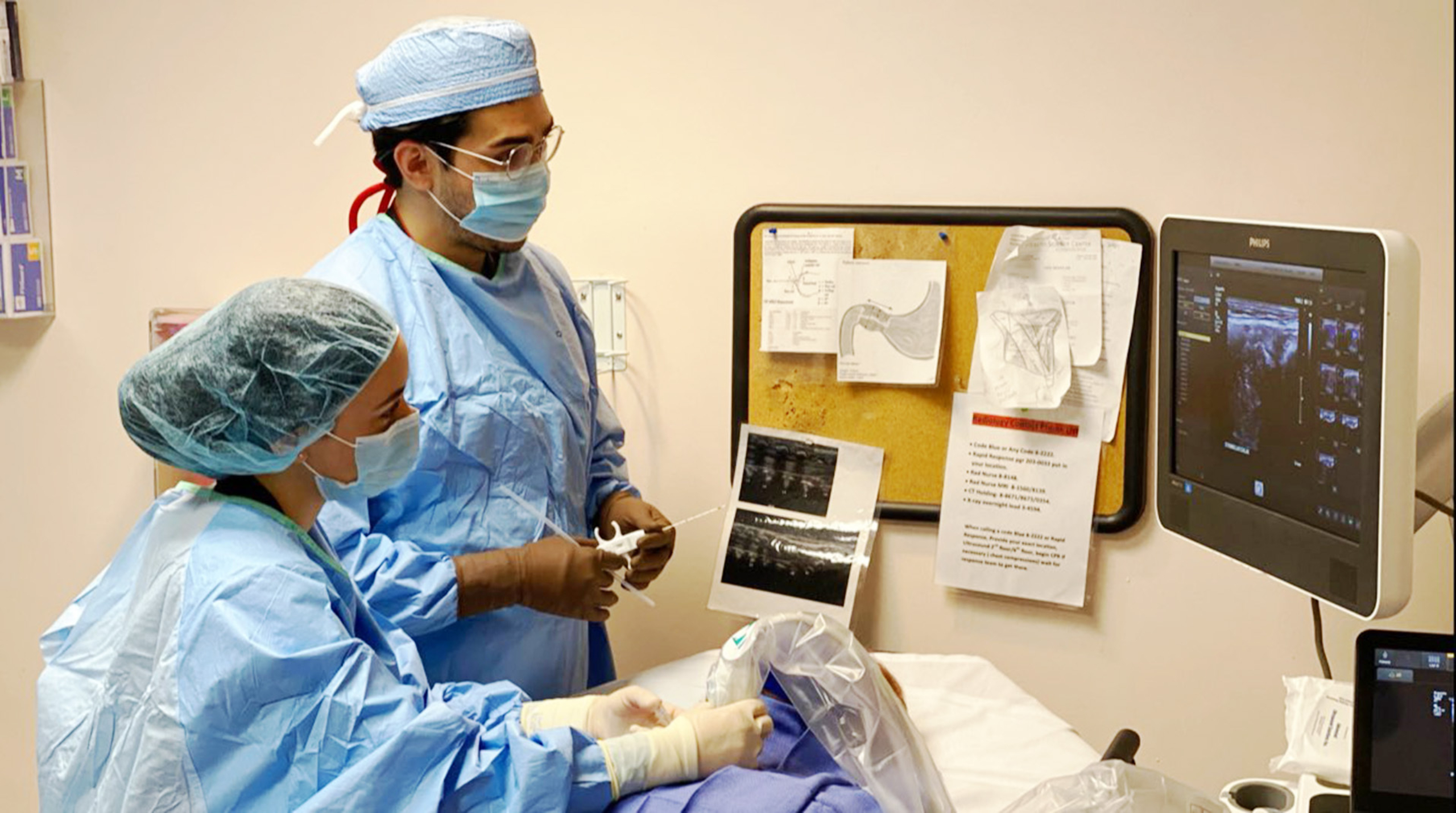 Charles Hyman and another physician treat a patient inside a patient room.