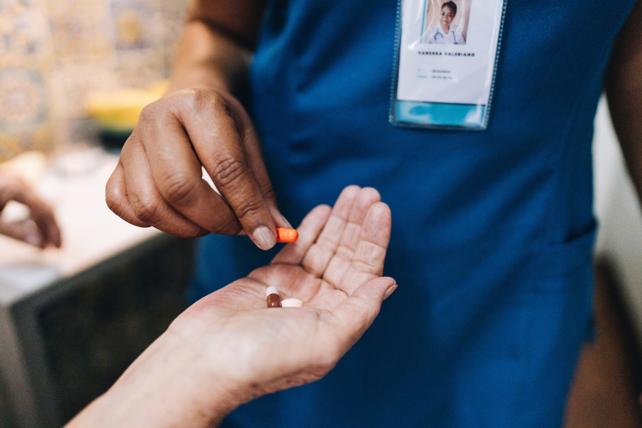 Close-up of nursing handing pills to a patient. 